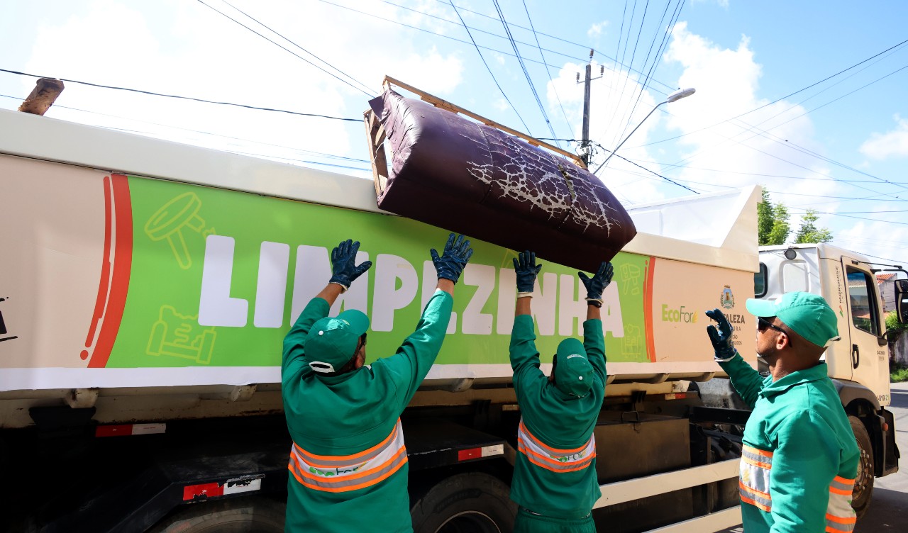 homens colocam um sofá velho no caminhão limpezinha